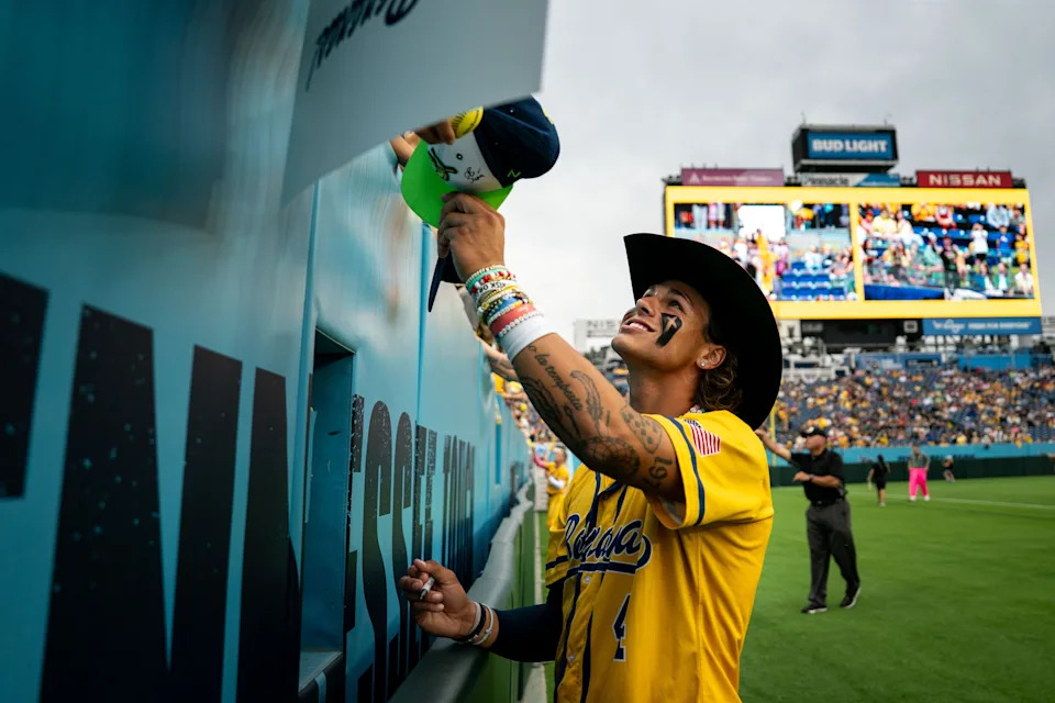 KJ from the Savannah Bananas holding a sign item to a fan in the stands.